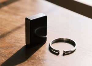 Black rectangular magnet placed beside a silver bracelet, used to test the magnetic property of silver and explore the question of is silver magnetic.