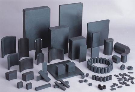 Assorted ferrite magnets in different geometric shapes (blocks, arcs, cylinders) displayed on a light background