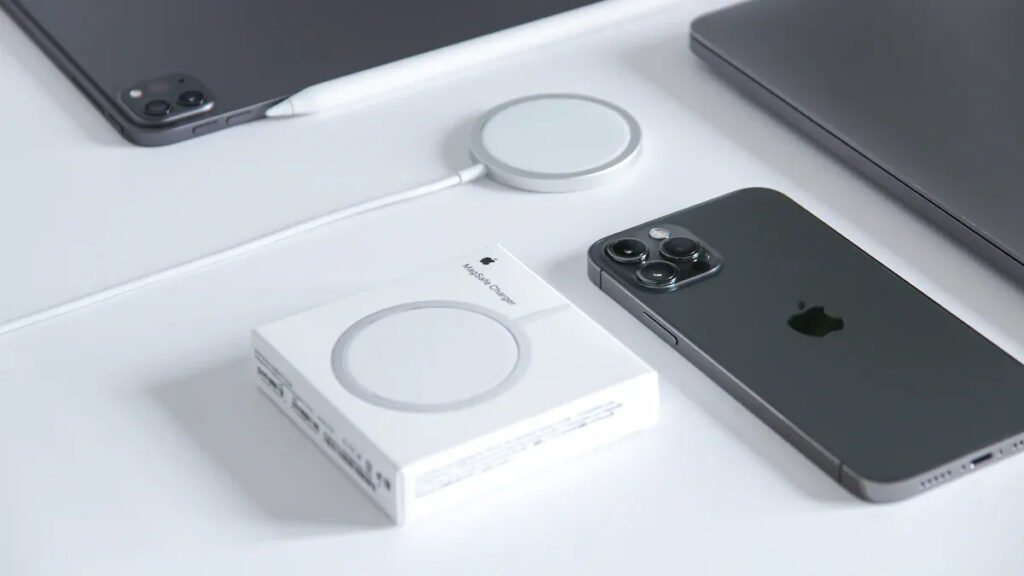 MagSafe charger, iPhone, and Apple products arranged on a desk, showcasing the ecosystem enabled by MagSafe magnet rings